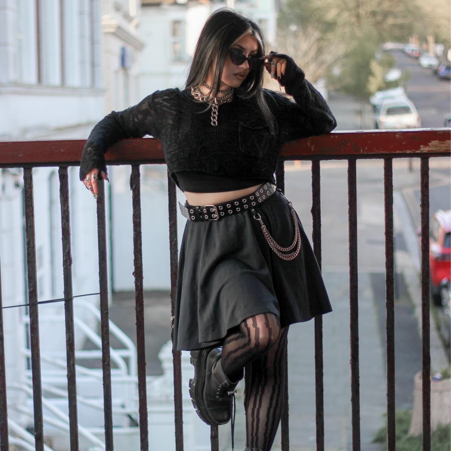 Woman in black outfit with skirt standing on a balcony