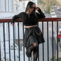 Woman in black outfit with skirt standing on a balcony